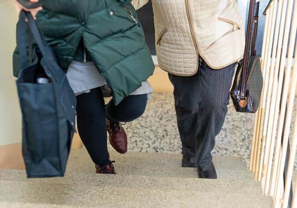 Mitarbeiterin des Besuchsdienstes unterstützt eine ältere Person bei einem gemeinsamen Weg außerhalb der Wohnung.